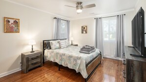 Ein Schlafzimmer mit einem Bett, Nachttischen, einem Deckenventilator und einem Fernseher.