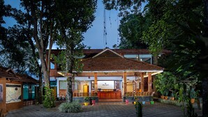 A hotel with a reception area, outdoor seating, and potted plants. - Coffee Routes Thekkady (Peermade)