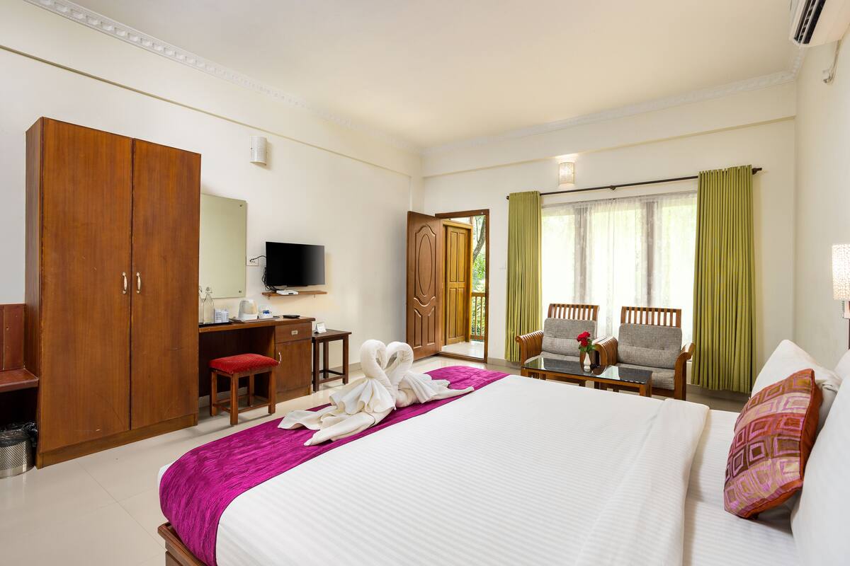 Una habitación de hotel con una cama grande, un escritorio con silla, un televisor y un armario.