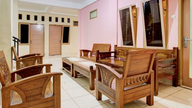 Une pièce meublée de meubles en bois, notamment des chaises et une table, et dont un des murs est peint en rose.