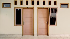 Deux portes portant les numéros 208 et 209, un sol carrelé et un mur orné de petites fenêtres rectangulaires.