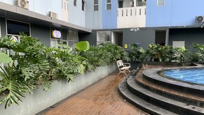 Ein Innenhof mit Pool, umgeben von Pflanzen und einer Bank.