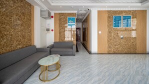 A modern lobby with a marble floor, grey sofas, and a small round table. - Cozrum Homes - Selina Residence (Ho Chi Minh City)