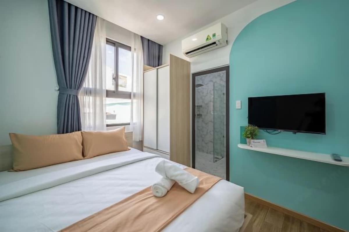 Une chambre d’hôtel avec un lit, une télévision, une douche et une fenêtre avec des rideaux.