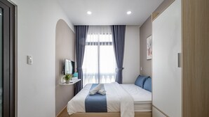A modern bedroom with a bed, a bedside table, a mirror, and a window with curtains. - Cozrum Homes - Selina Residence (Ho Chi Minh City)