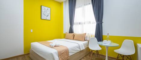 A room with a bed, a small round table, two chairs, and a window with curtains.