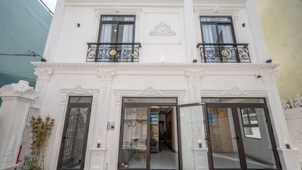 A two-story building with a grand entrance, large glass doors, and decorative iron railings on the balconies. - Cozrum Homes - Selina Residence (Ho Chi Minh City)