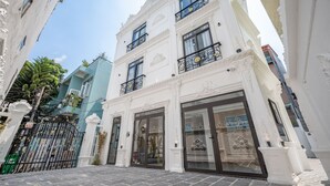 A building with ornate white facades, large glass doors, and a gated entrance. - Cozrum Homes - Selina Residence (Ho Chi Minh City)