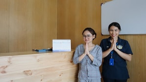 Two individuals standing in front of a wooden desk with a calendar and a whiteboard. - Hotel O Room Transit By At (Tangerang)