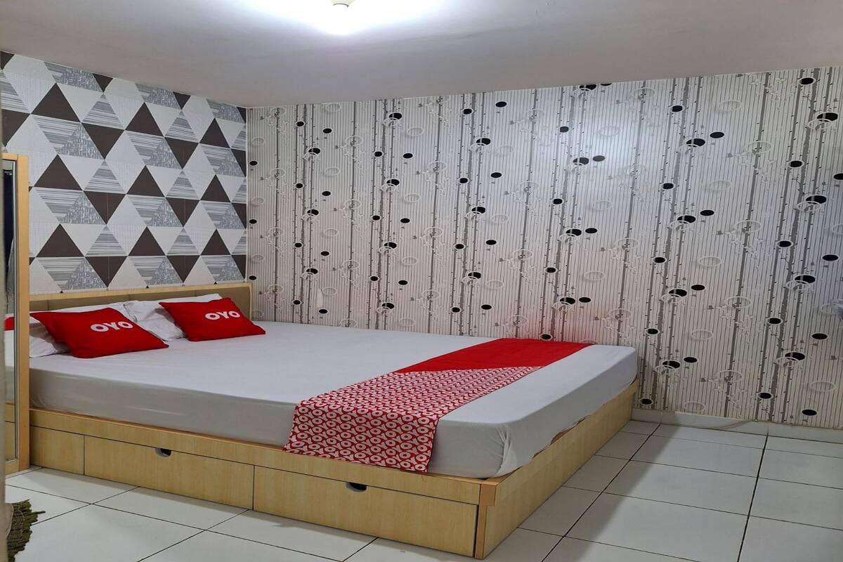 A bedroom with a bed, wooden headboard, and patterned wallpaper.