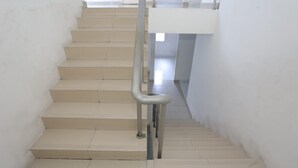 A staircase with a metal handrail, white walls, and a view of an upper floor. - Hotel O Room Transit By At (Tangerang)
