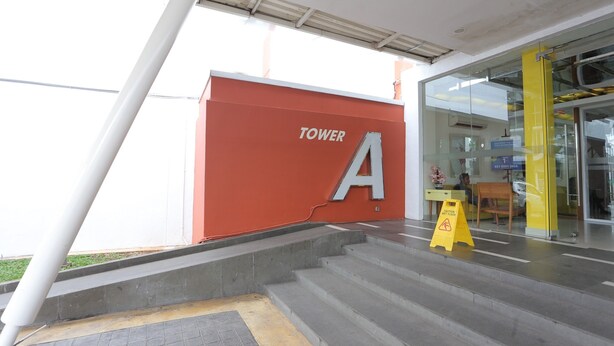 A hotel entrance with a red wall featuring a large 'A' and the word 'TOWER'. - Hotel O Room Transit By At (Tangerang)