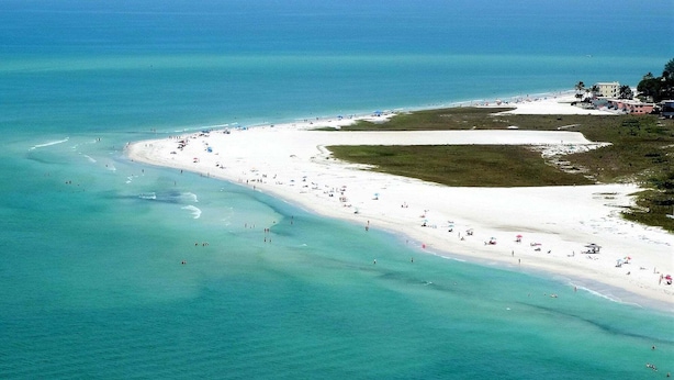 A coastal beach with a wide sandy area, clear turquoise waters, and a few buildings in the background. - Gertrude's Siesta | Pool & Spa, 100% Private, 5-min bike to Siesta Key Beach, 3-miles to Village! (Siesta Key)