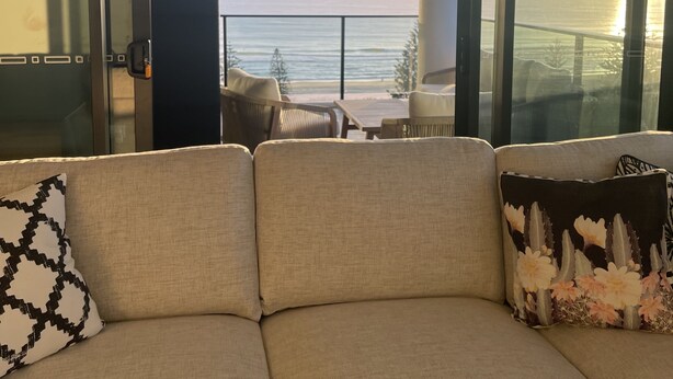 Un balcon avec un canapé et des fauteuils, d’où l’on peut admirer le coucher de soleil sur l’océan.