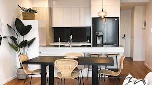 Une cuisine moderne avec des armoires blanches, un comptoir noir et un réfrigérateur en acier inoxydable.