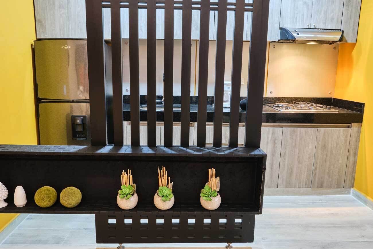 A kitchen with a black grill, a yellow wall, and a wooden cabinet.