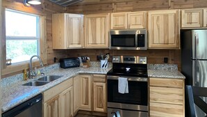 A modern kitchen with wooden cabinets, a microwave, a toaster, an oven, and a dishwasher. - Lakeside House & Cabin Boat Ramp, Dock, & Fire Pit on Possum Kingdom Lake (Graham)