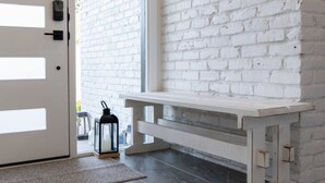 A modern interior with a white brick wall, a bench, and a door leading outside.