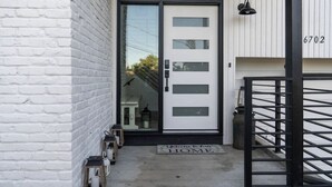 A modern entrance with a glass door, a white brick wall, and a metal gate.