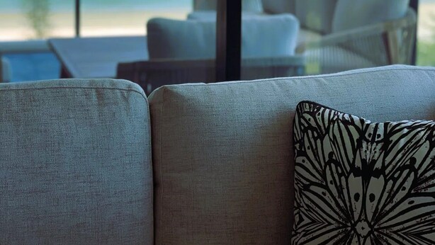 A balcony with a view of the ocean, a sofa, and a patterned pillow. - Boardwalk Burleigh Beach 1 bed (Burleigh Heads)