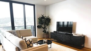 A modern living room with a sofa, coffee table, and TV stand. - Boardwalk Burleigh Beach 1 bed (Burleigh Heads)