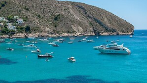 Una zona costera con numerosos barcos y yates anclados en aguas azules y cristalinas.