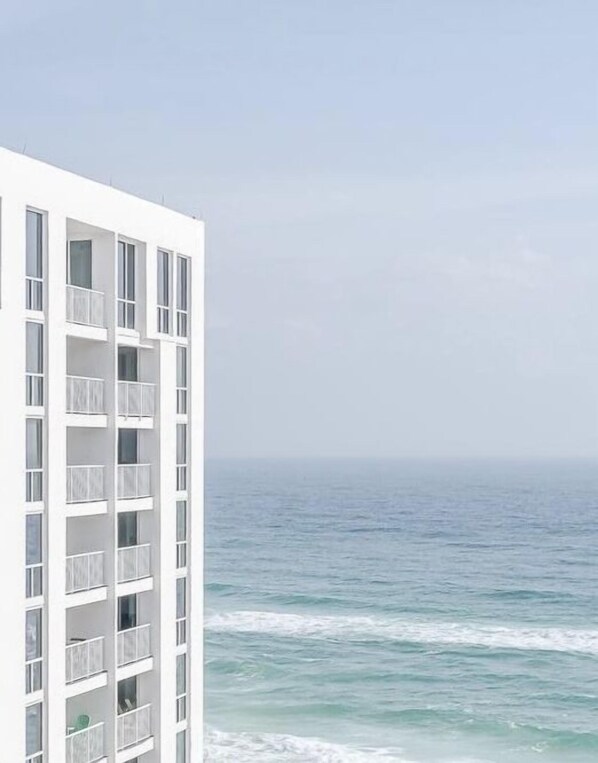 A white building with multiple balconies overlooking the ocean.