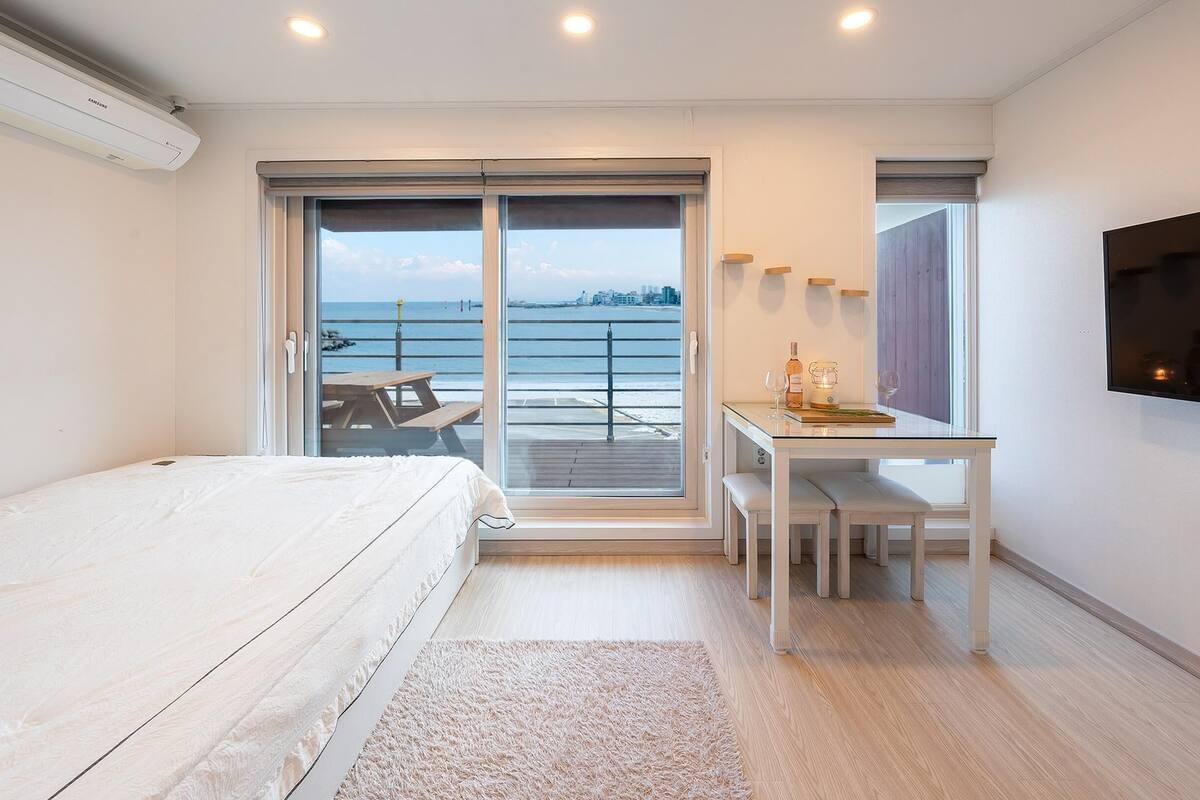 A bedroom with a bed, a desk, and a TV.