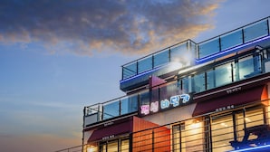 A modern building with a glass facade and a neon sign. - Goseong Badasga per Osyeonbyu Pension (Goseong)