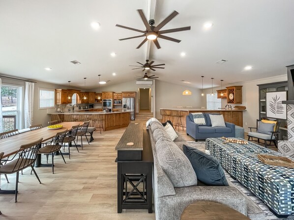 A spacious living area with a large sofa, dining table, and kitchen in the background.