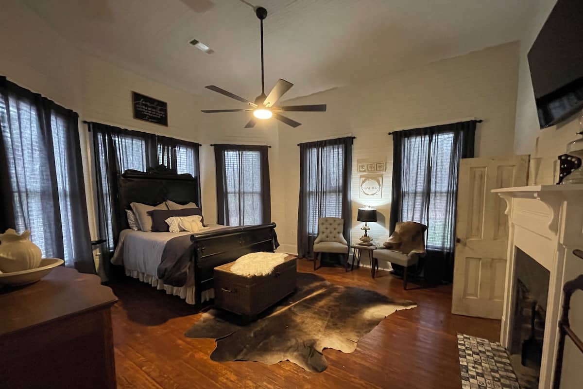 Un dormitori espaiós amb un llit gran, un ventilador de sostre i una llar de foc.