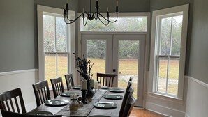Un comedor con una gran mesa de madera dispuesta para seis personas, rodeada de sillas de madera oscura.