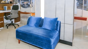 A blue velvet sofa with wooden legs in a modern office setting. - Collection O Fortune 88 Kamala Lagoon Reception at Indomaret and White Forest (Bekasi)