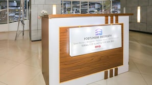 A reception desk with a sign for Fortune88 Property, including contact information and location details. - Collection O Fortune 88 Kamala Lagoon Reception at Indomaret and White Forest (Bekasi)