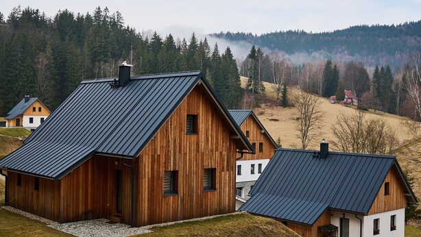 A cluster of wooden cabins with metal roofs, set on a grassy hill with a forested backdrop. - Pod lesem by Interhome (Smržovka)
