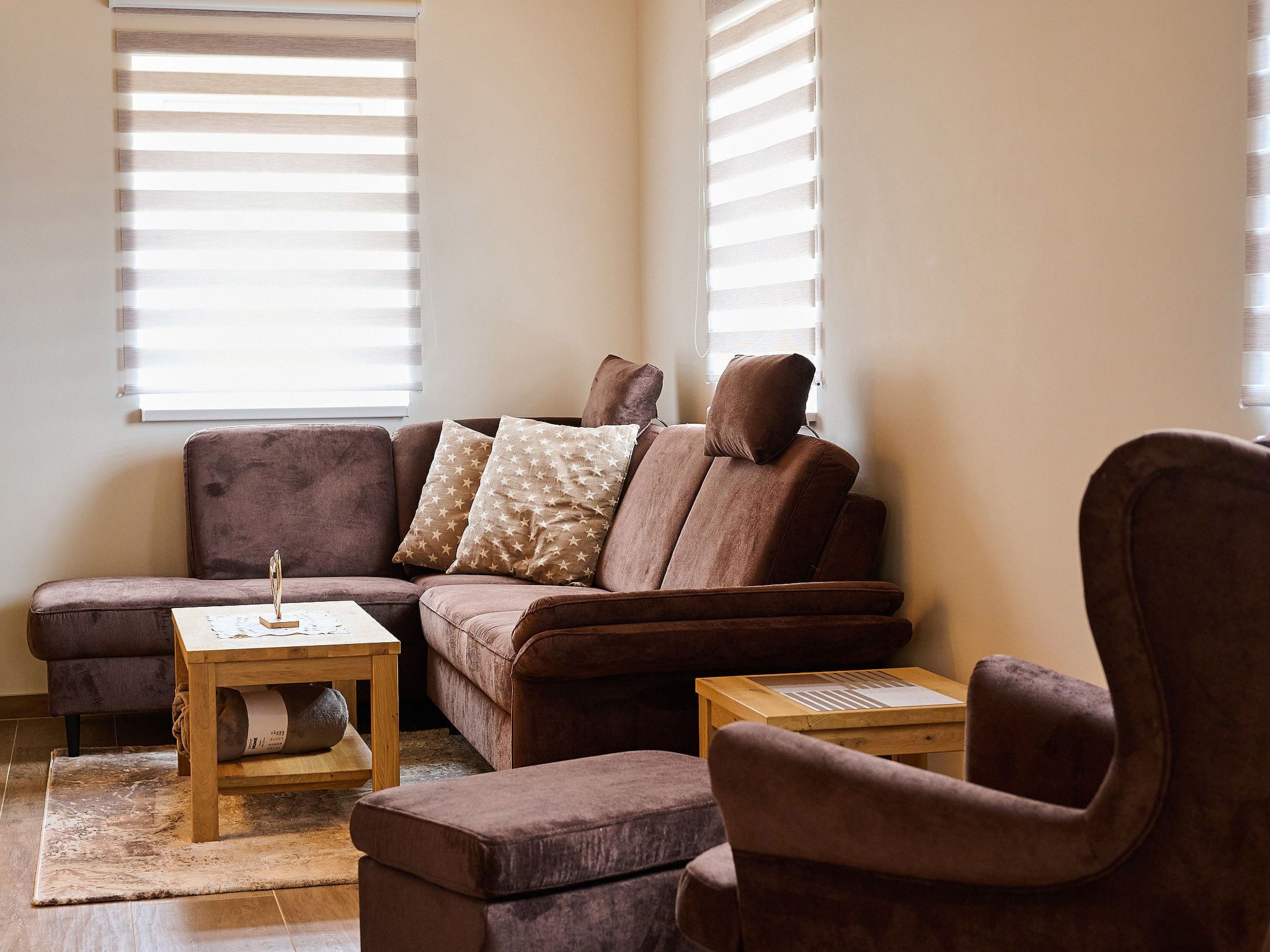 Ein Wohnzimmer mit einem braunen Sofa, zwei passenden Sesseln, einem Holztisch und einem kleinen Beistelltisch.