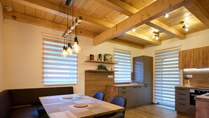 A modern kitchen with wooden cabinets, a dining area with a table and chairs, and a built-in bench. - Pod lesem by Interhome (Smržovka)