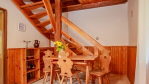 A wooden dining table with four chairs, a vase with sunflowers, and a wooden cabinet with shelves. - Žabovřesky by Interhome (Dehtáře)
