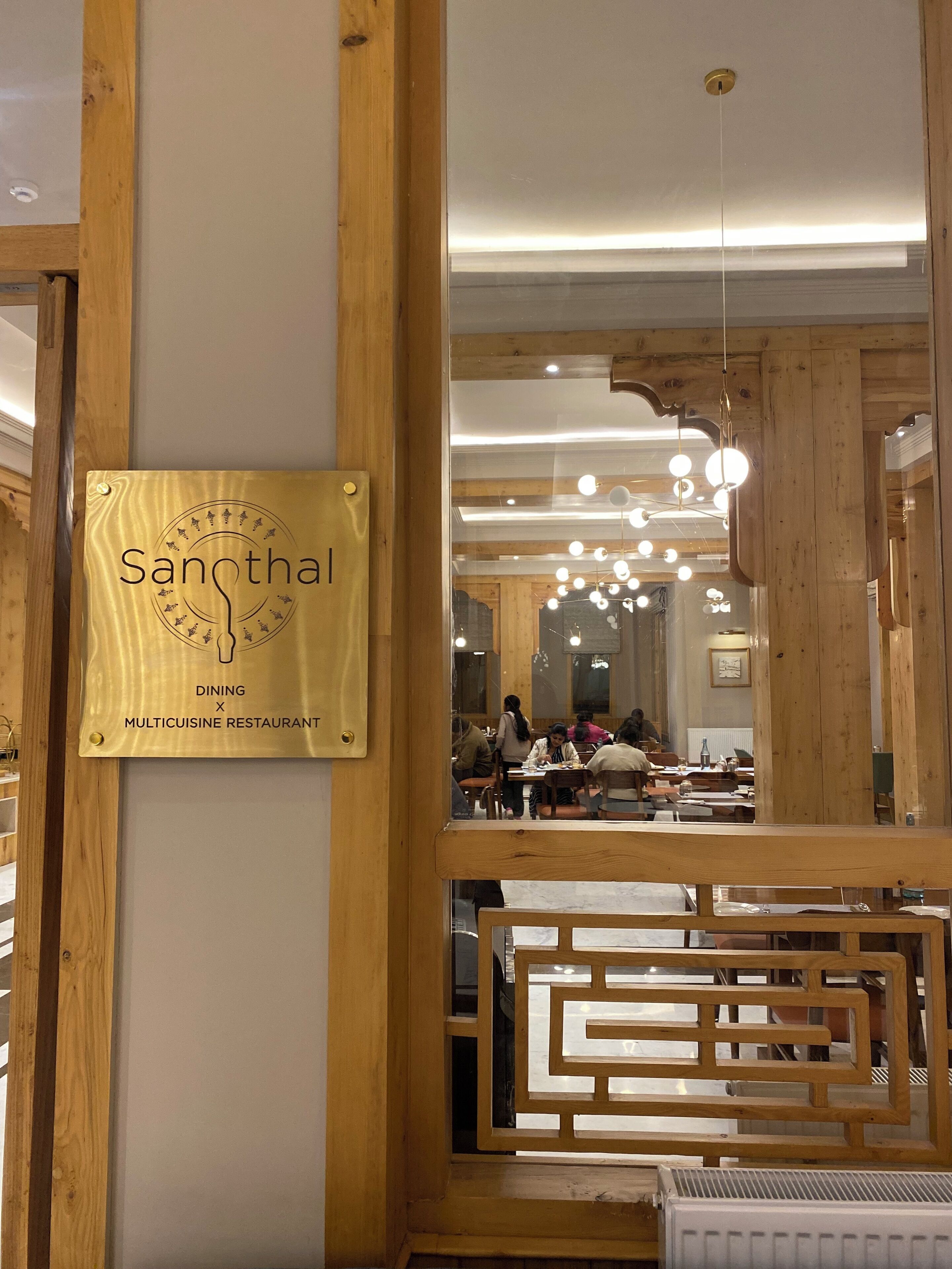 A restaurant interior with wooden beams, a dining area, and hanging spherical lights.