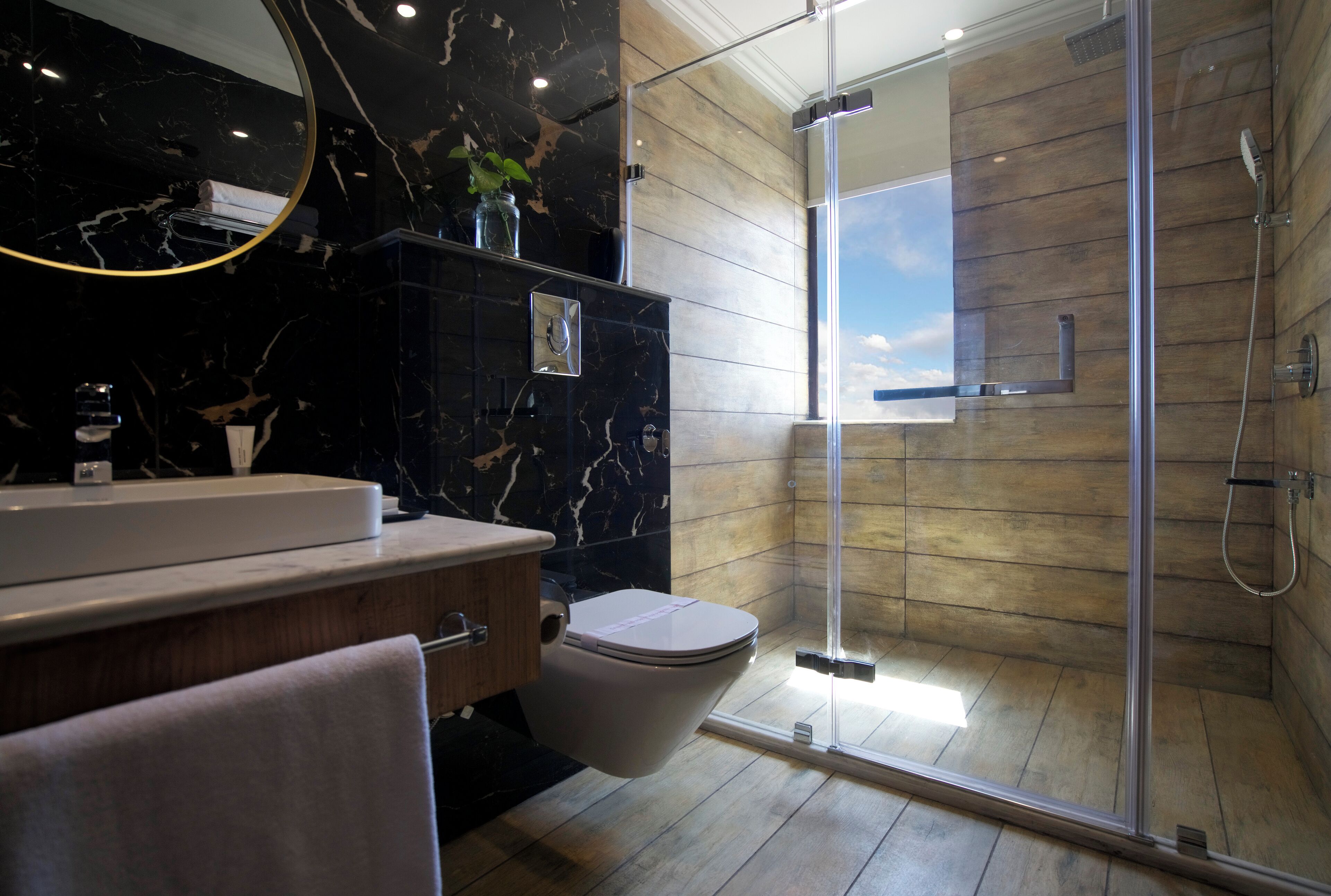 A modern bathroom with a marble vanity, a toilet, and a glass-enclosed shower.