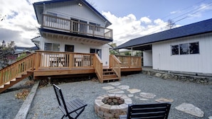 A two-story house with a wooden deck and a stone fire pit. - Bright & Airy 4 Bedroom Villa in North Tacoma (Tacoma)