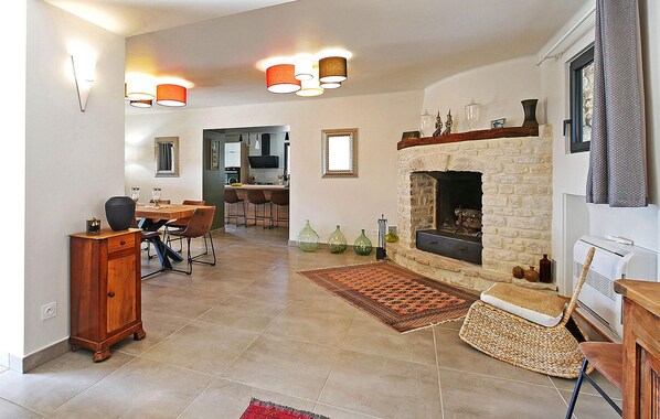 Una sala de estar amplia con chimenea, un comedor y una cocina al fondo.