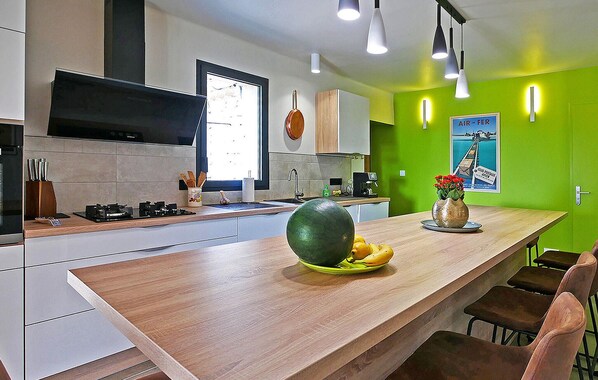 Una cocina moderna con encimera de madera, una isla grande y una pared verde decorativa.