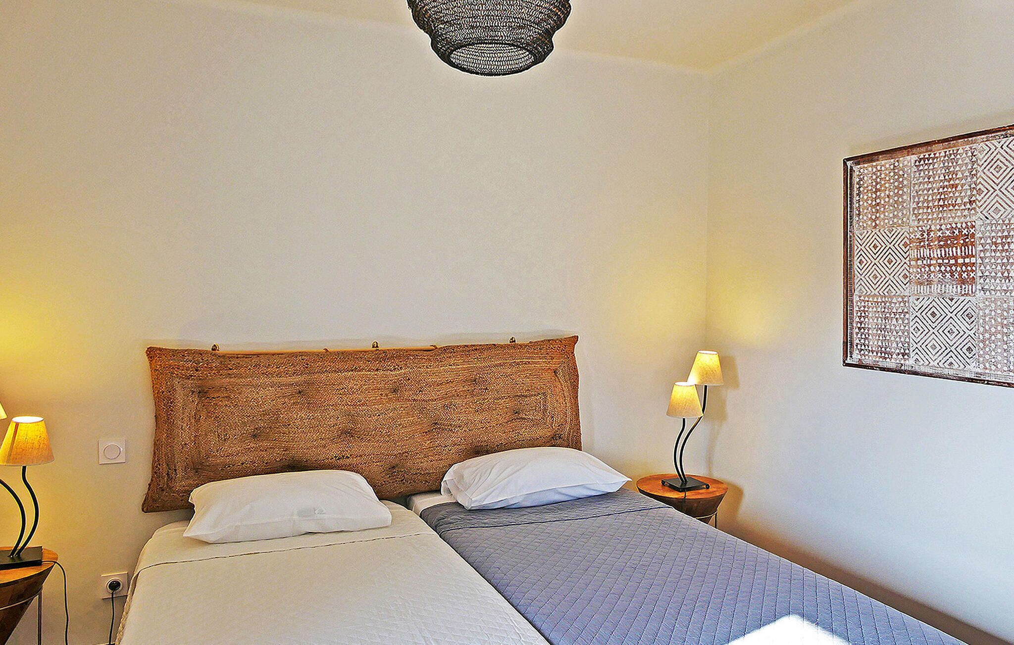 Un dormitorio con cama, dos lámparas de noche, un cuadro en la pared y una lámpara de techo.