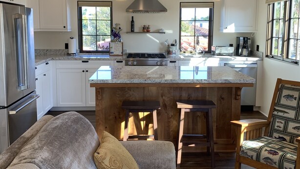Una cocina moderna con una isla central, vigas de madera e iluminación colgante.