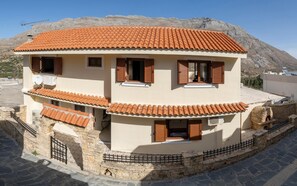 A two-story building with a tiled roof, stone walls, and wooden shutters.