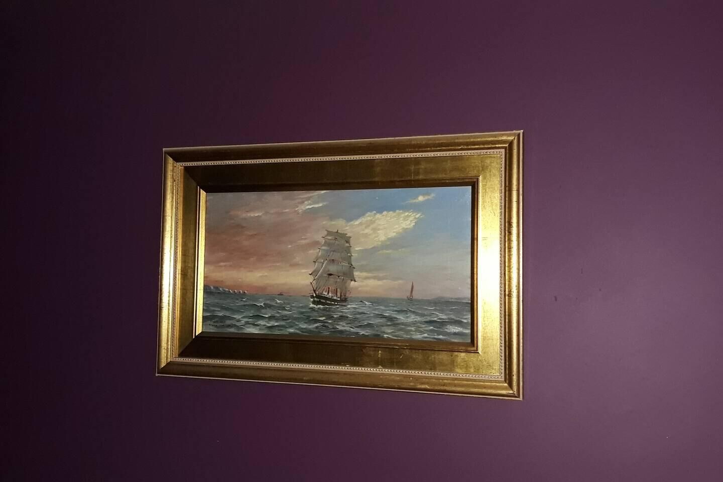 Un cuadro enmarco que muestra un barco a vela en el mar.