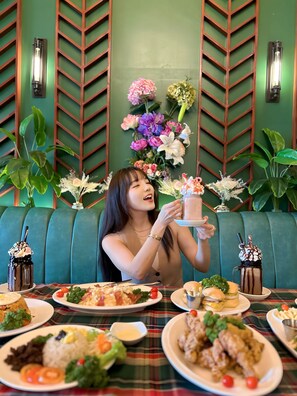 A person seated at a table with various dishes, including rice, meat, and vegetables, in a room with green walls and wooden paneling. - Clark CU Hotel (Angeles City)