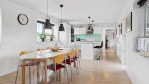 Une cuisine moderne avec des meubles blancs, un îlot central et des luminaires suspendus.