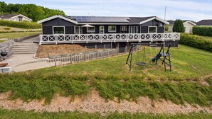 Une maison moderne dotée d’un patio couvert, de panneaux solaires et d’une balançoire.